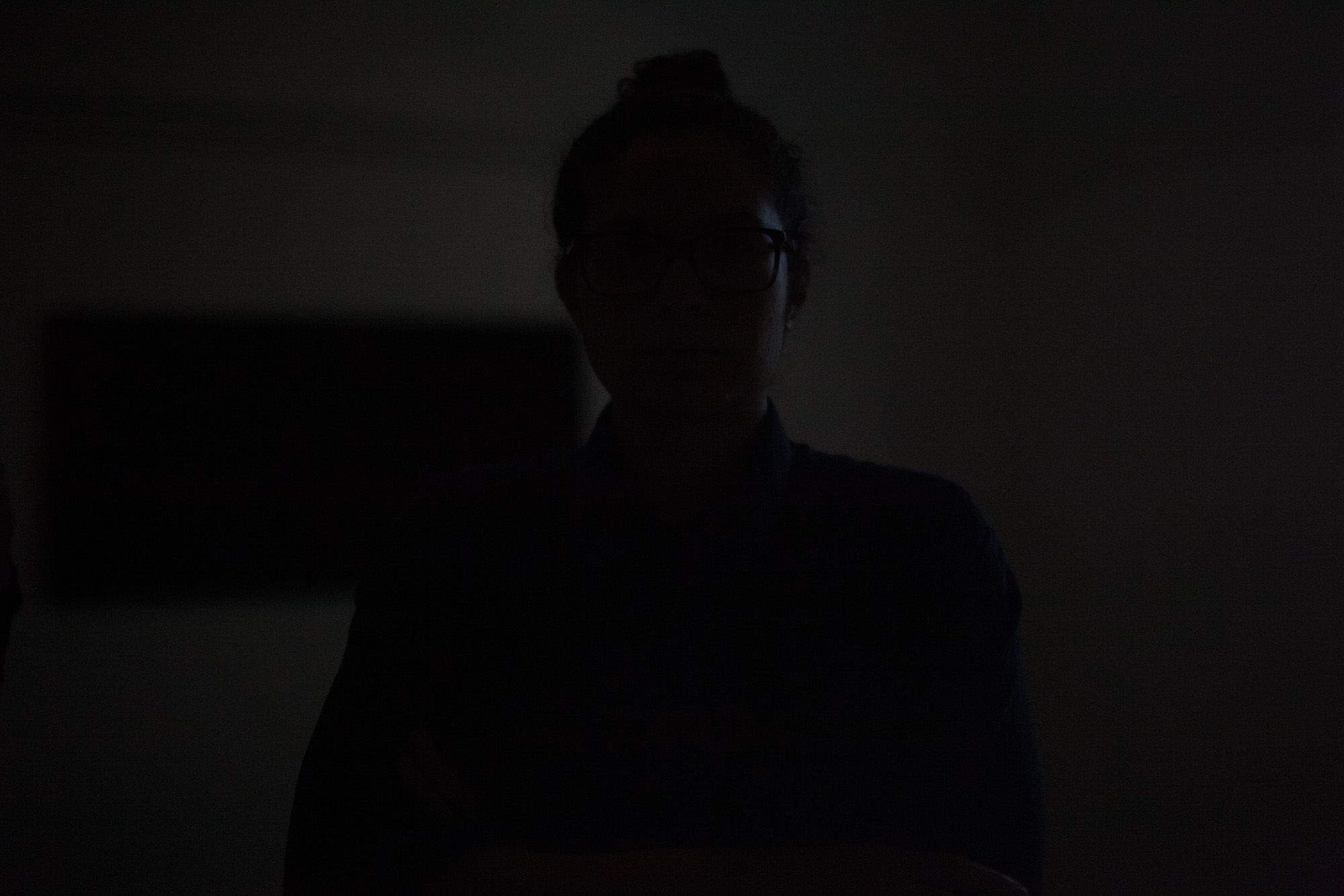 Close-up of the viewer’s shadowed reflection in a black mirrored artwork.