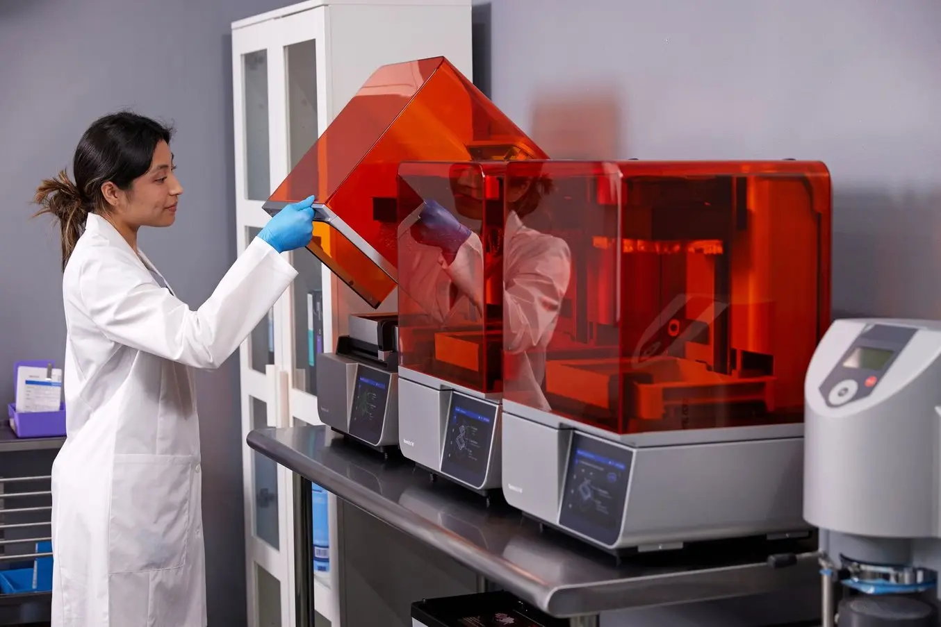 A technician opens a Formlabs Form 4B 3D printer in a lab setting.
