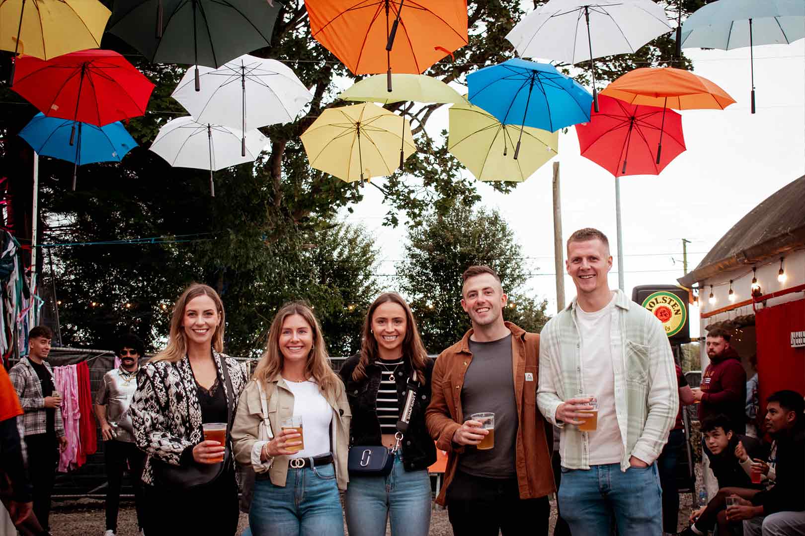 A group of festival goers pose for a photo under the umbrellas canopy at Fool Moon Rising festival