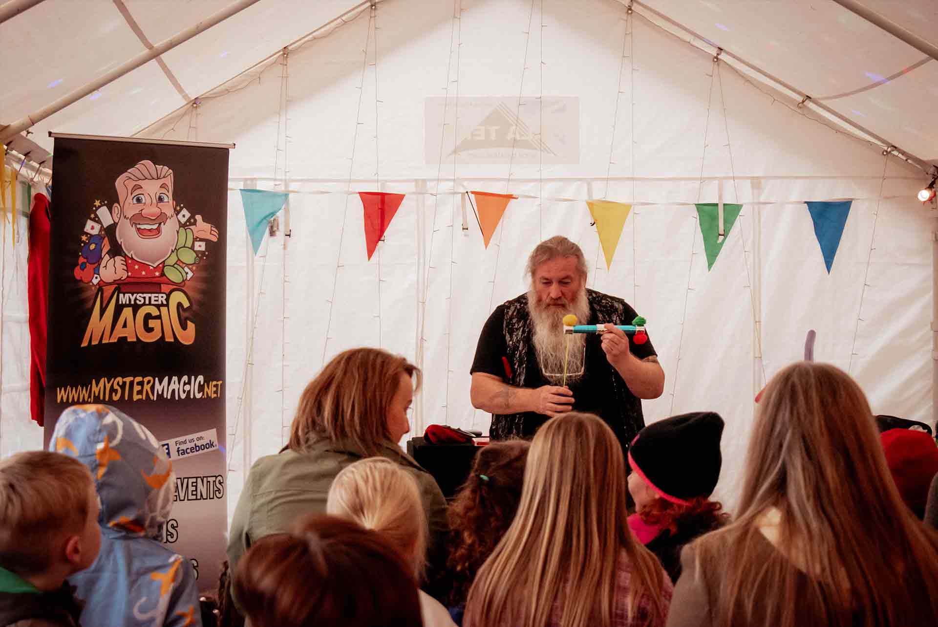 A magician does a trick in the Magic tent at Full Moon Rising Festival