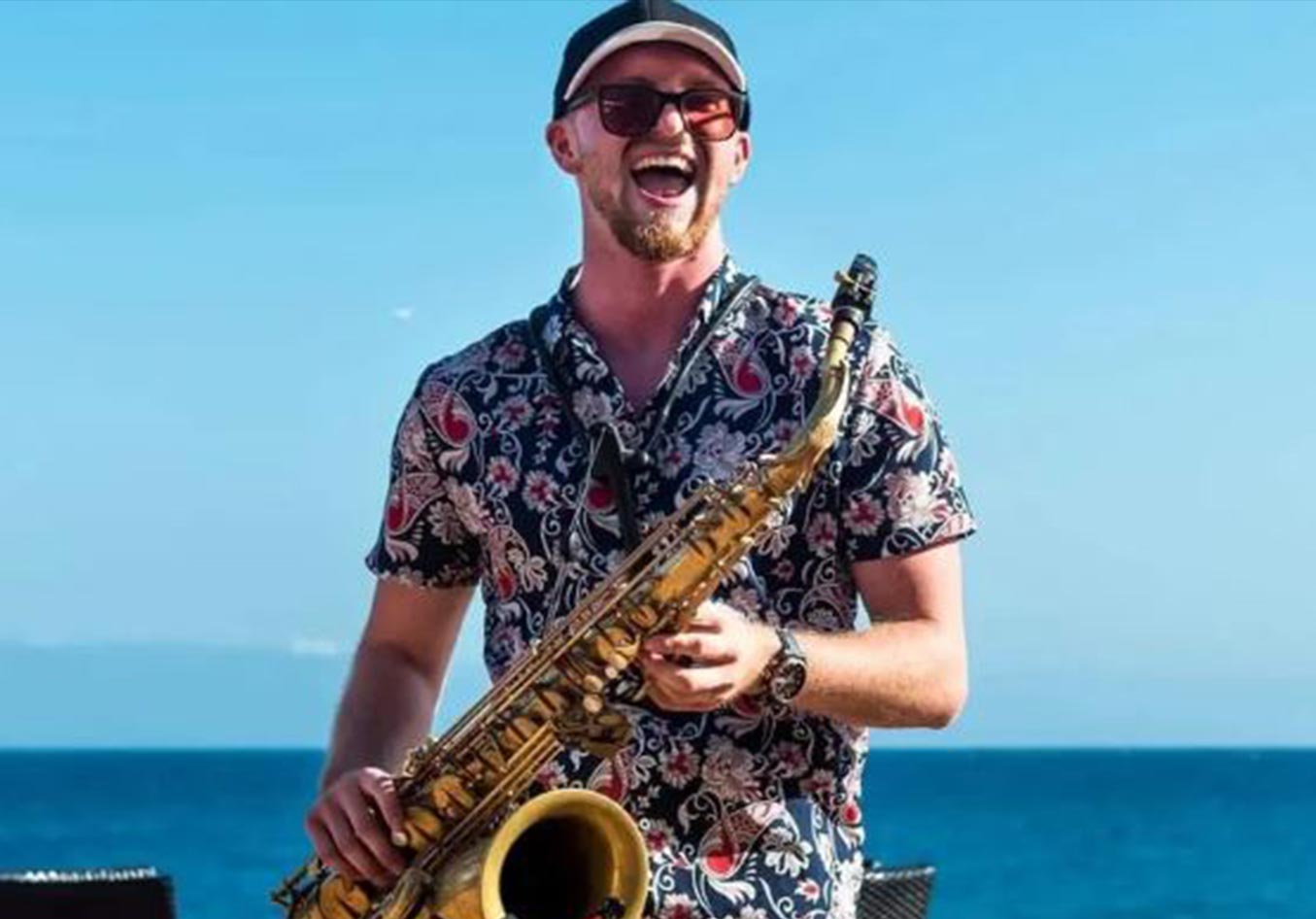 Hanson Sax on a beach with his Saxophone 
