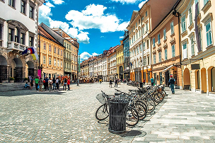 Cobblestone street lined with bicycles and historic European buildings under a blue sky with scattered clouds.