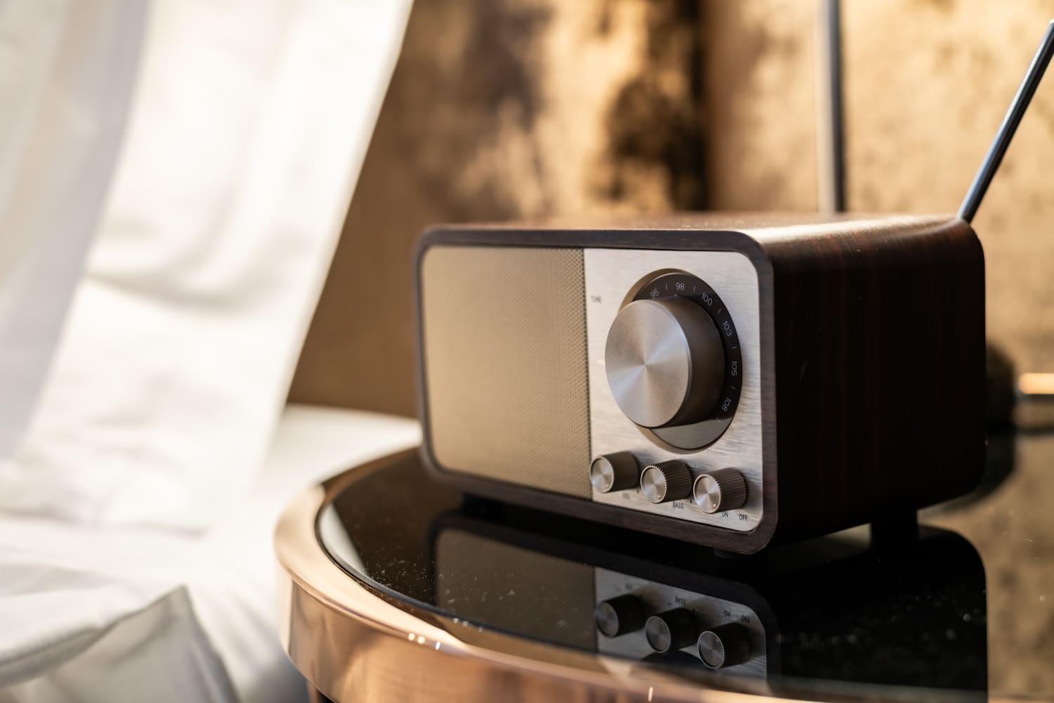 Retro radio with tuning dial and knobs on a glossy black table surface.