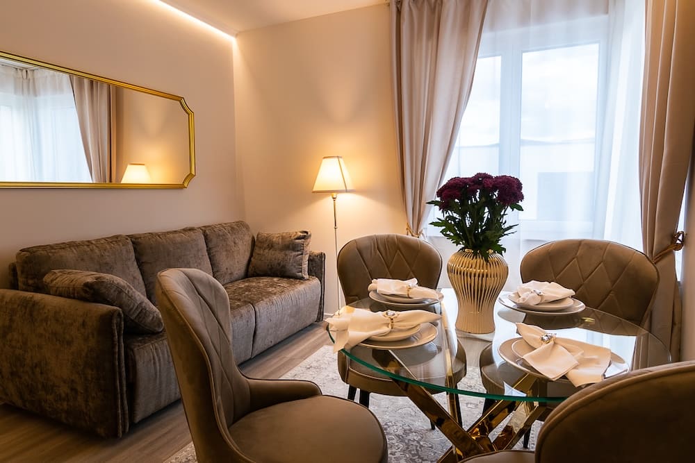 Cozy dining and living area with a glass table set for four and a plush sofa under a large mirror.