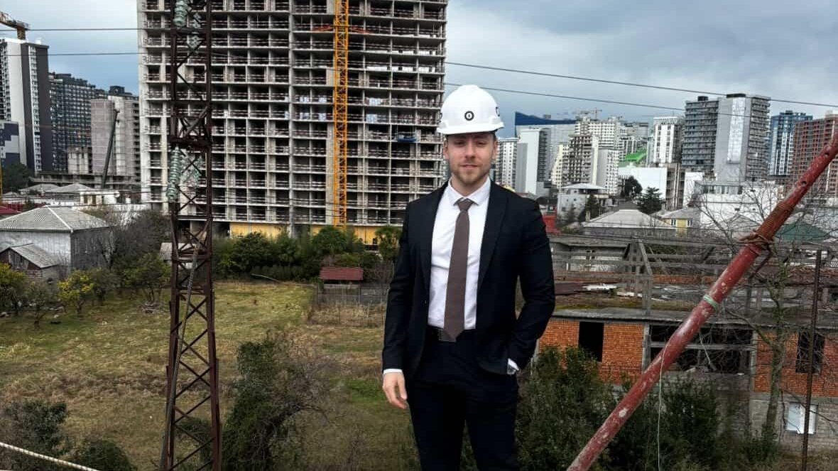 Un membre de l'équipe France Finance International sur un chantier en Géorgie, devant une tour en construction