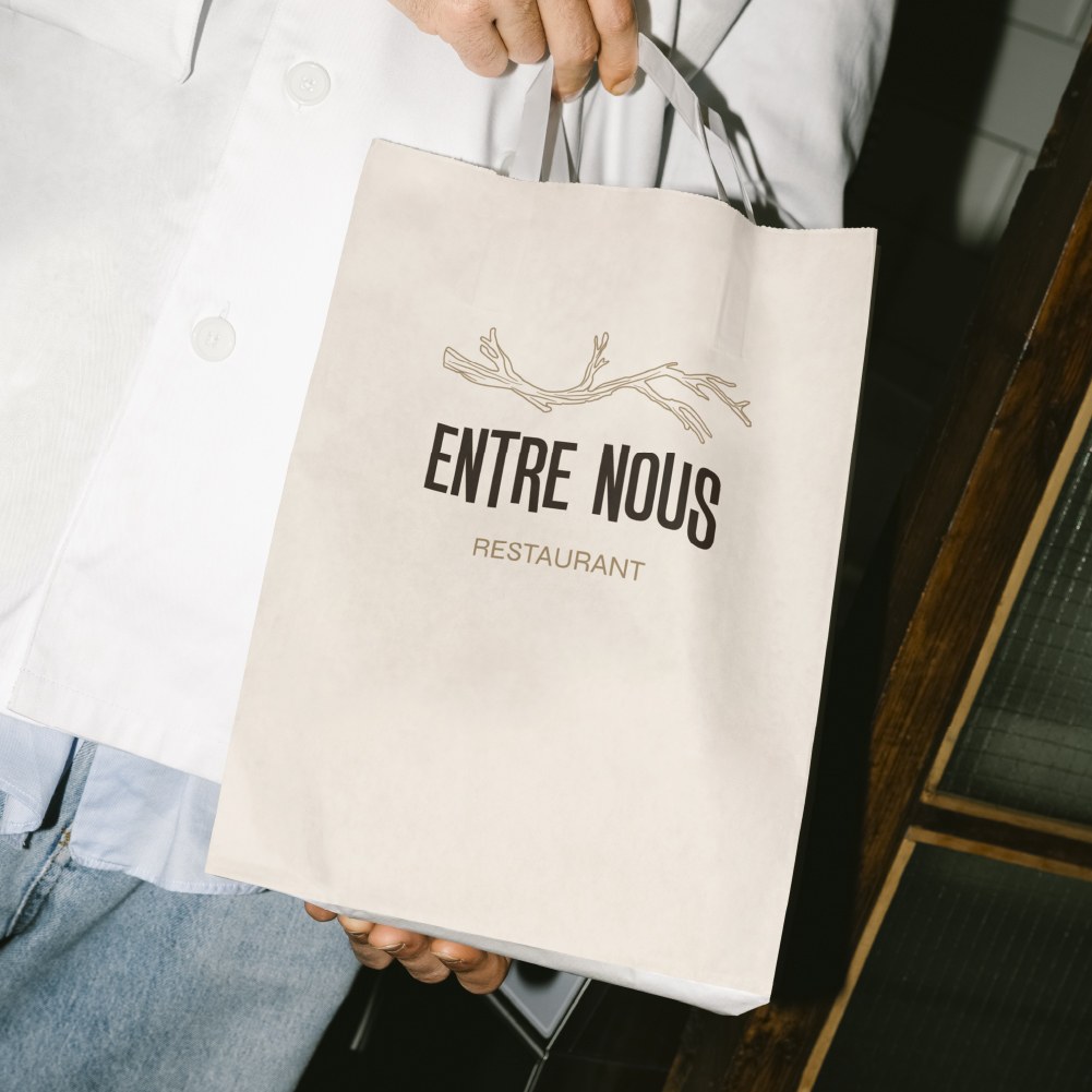 Sac en papier Entre Nous tenu par un cuisinier