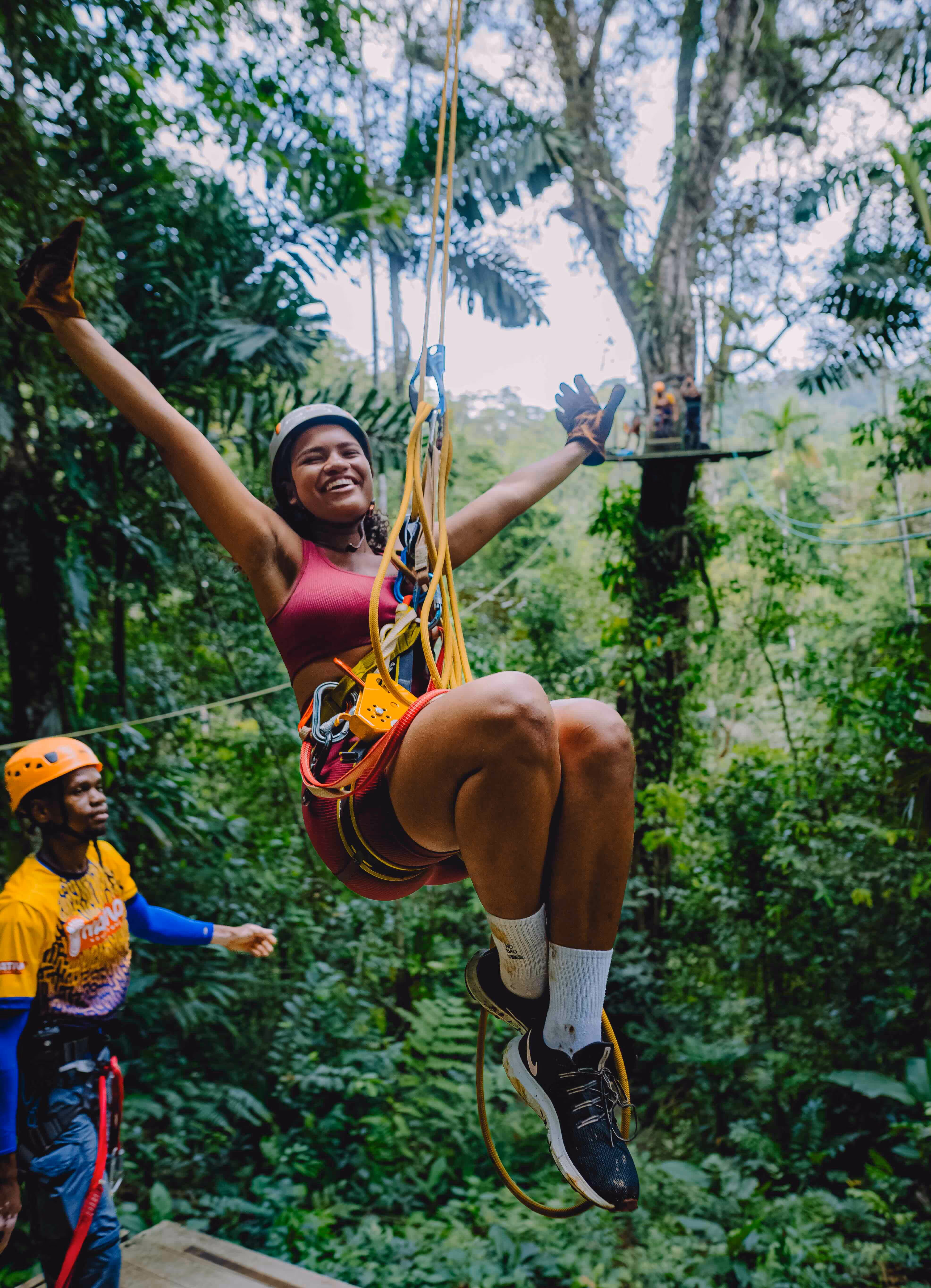 A girl smiling while Zip lining trough the Rainforest.