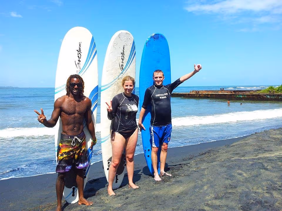 Surfing beginners cheering with their teacher in front of their surf boards.