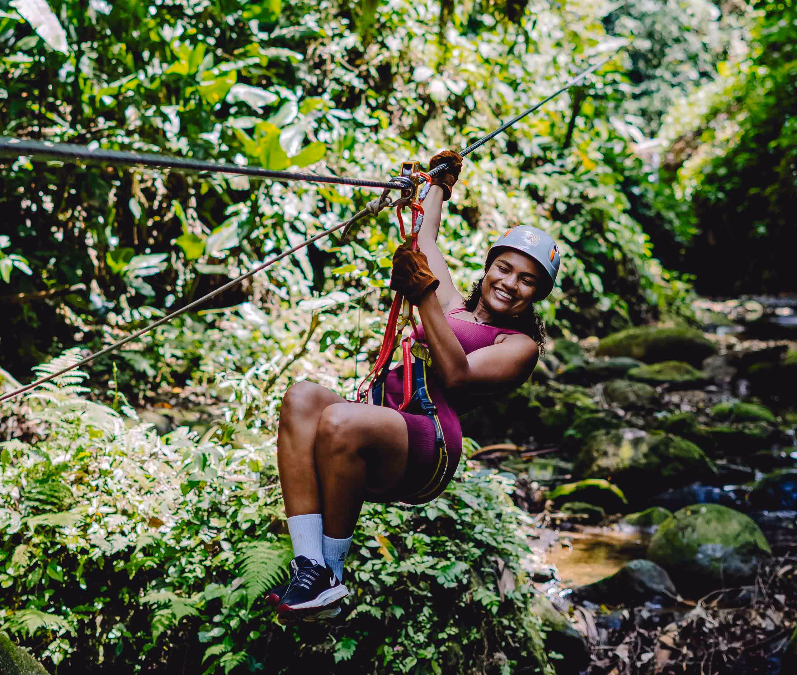 A girl smiling while zip lining trough the Costa Rican jungle.