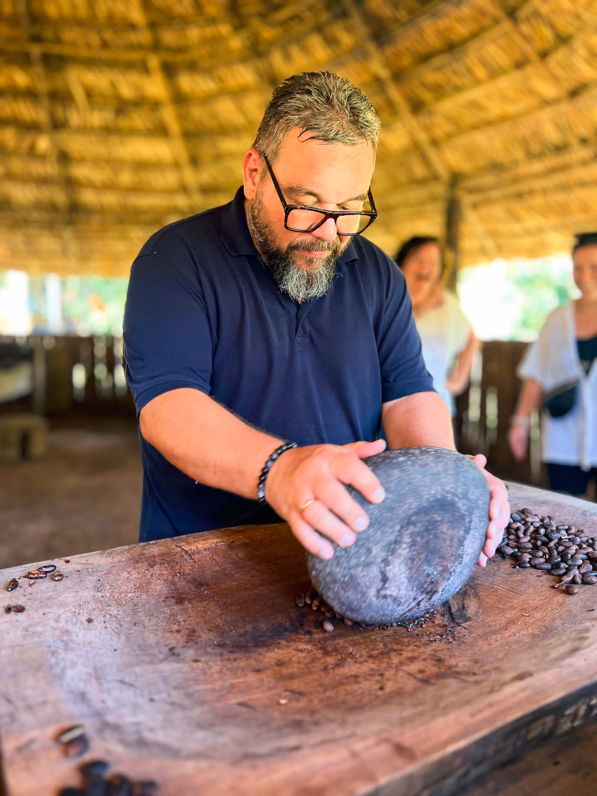 A sticos guest grinding cacao beans with a rock to make Chocolate at the BriBri tribe.