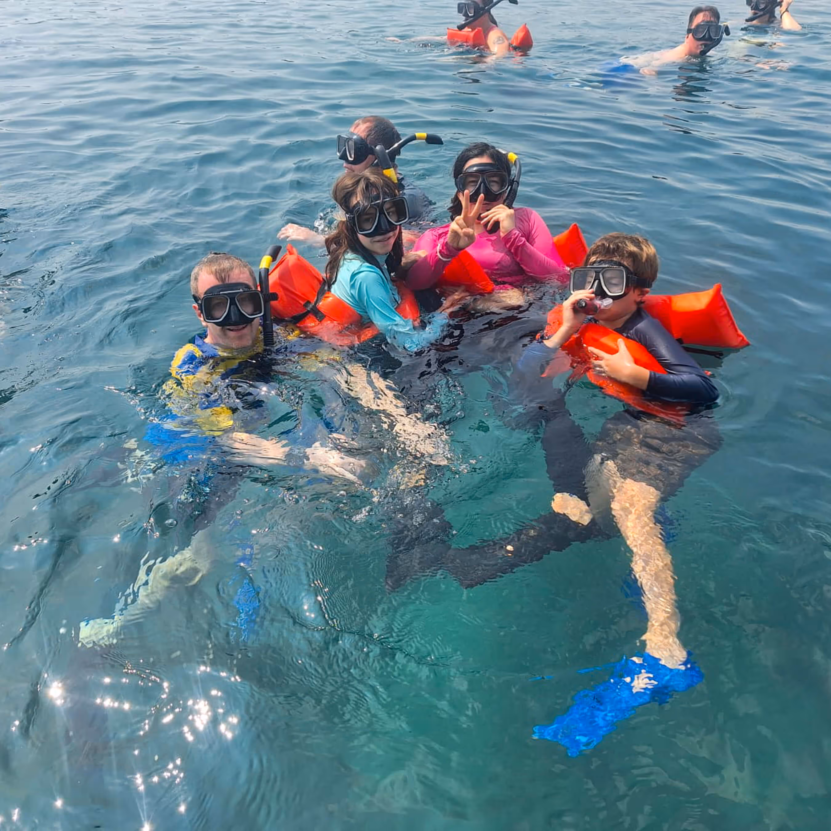 A family smiling for a group photo while snorkeling in the Costa Rican Caribbean Sea.