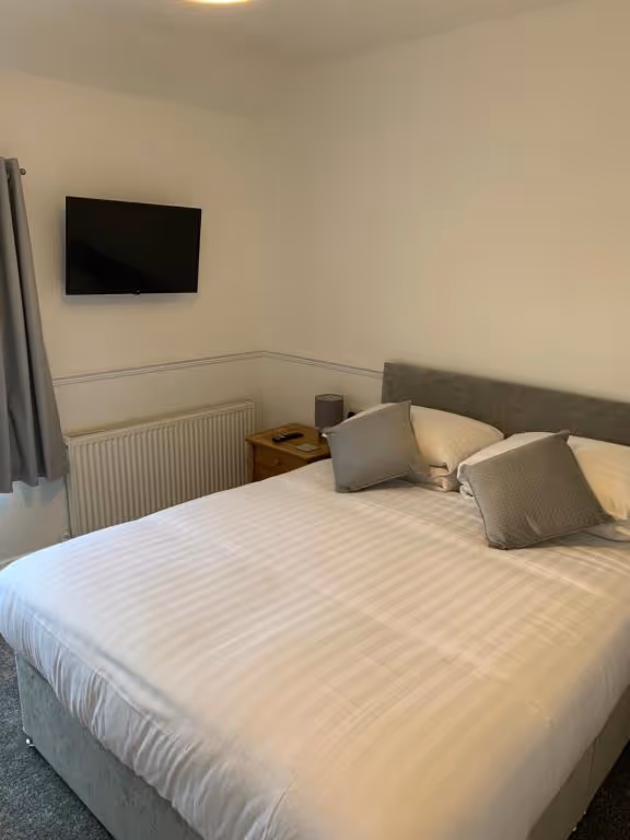 A bed with a flat screen TV on the wall.