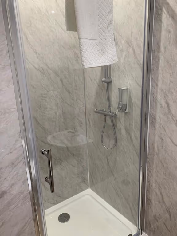 A shower with a white towel hanging on the side.