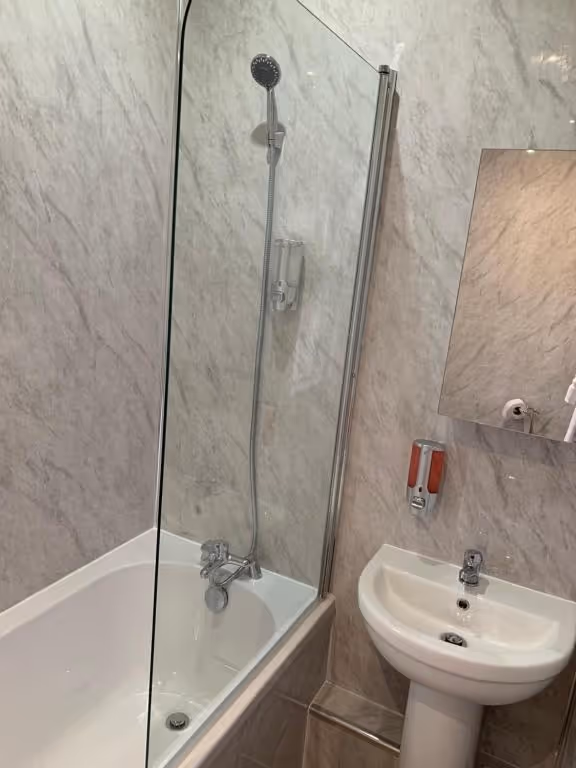 A white bathroom with a shower, sink, and mirror.