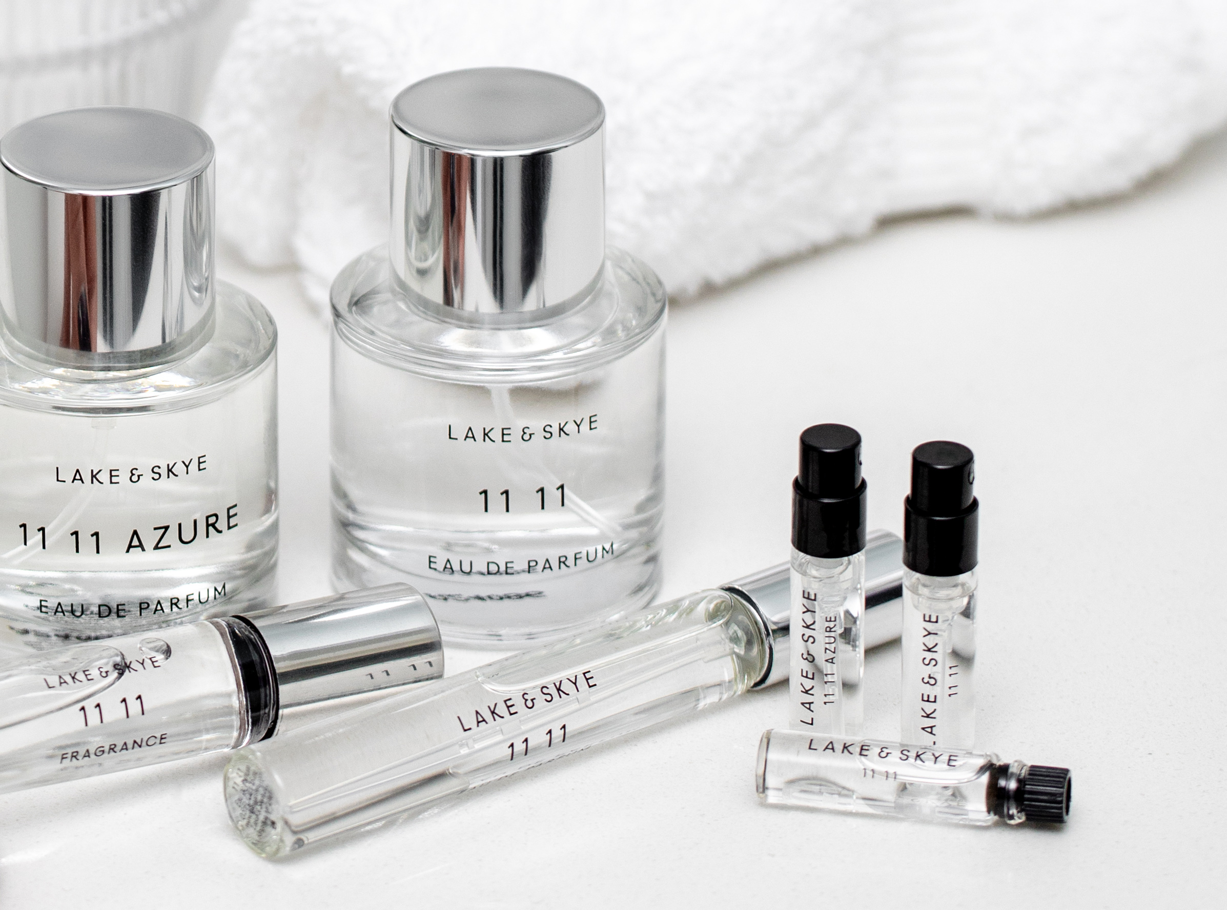 Lake & Skye perfume bottles, rollerball oils, and sample vials on white counter, minimalist fragrance branding.