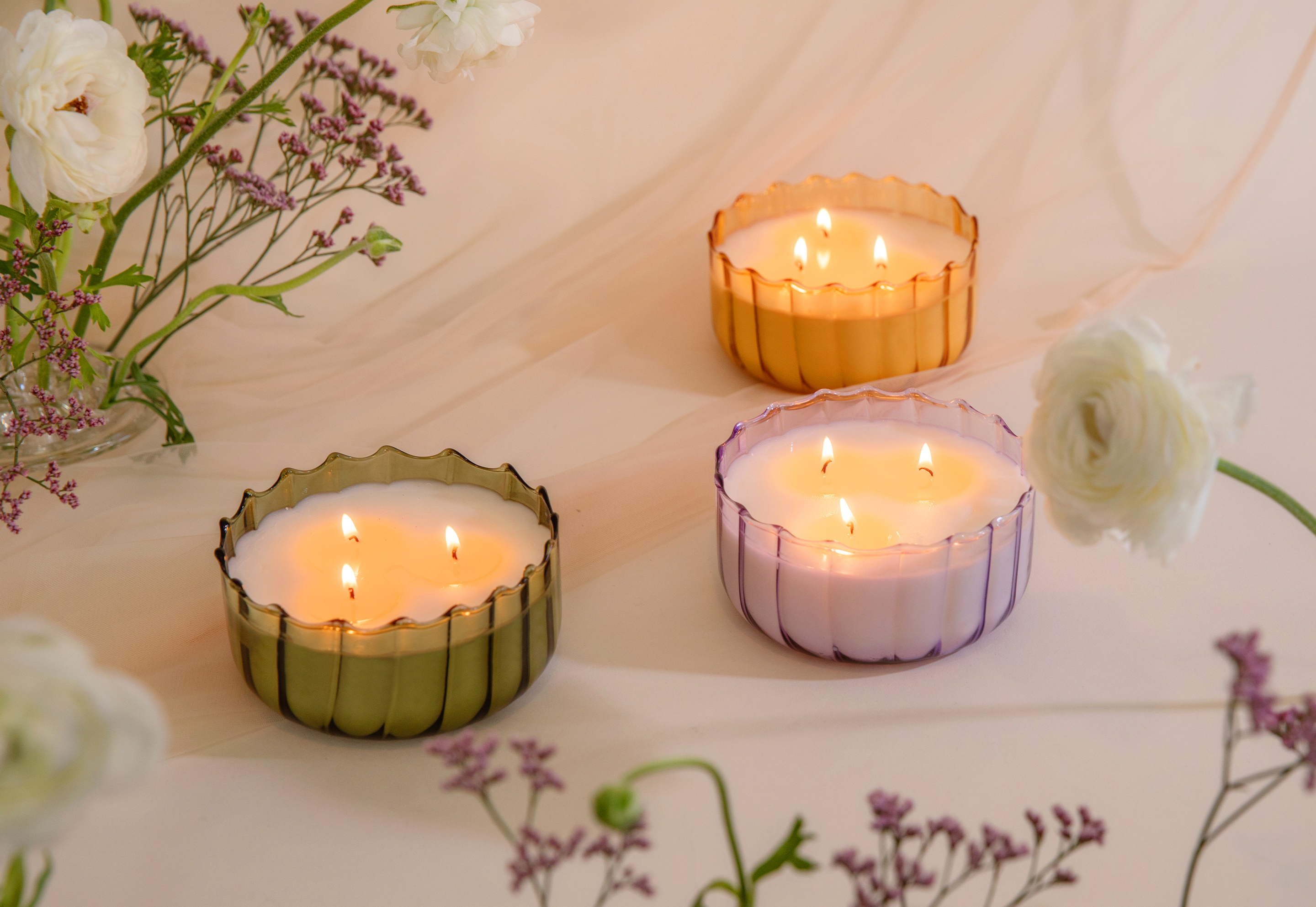 Paddywax Candles trio of scalloped glass candles in green, gold, and lavender vessels styled with florals for product photography
