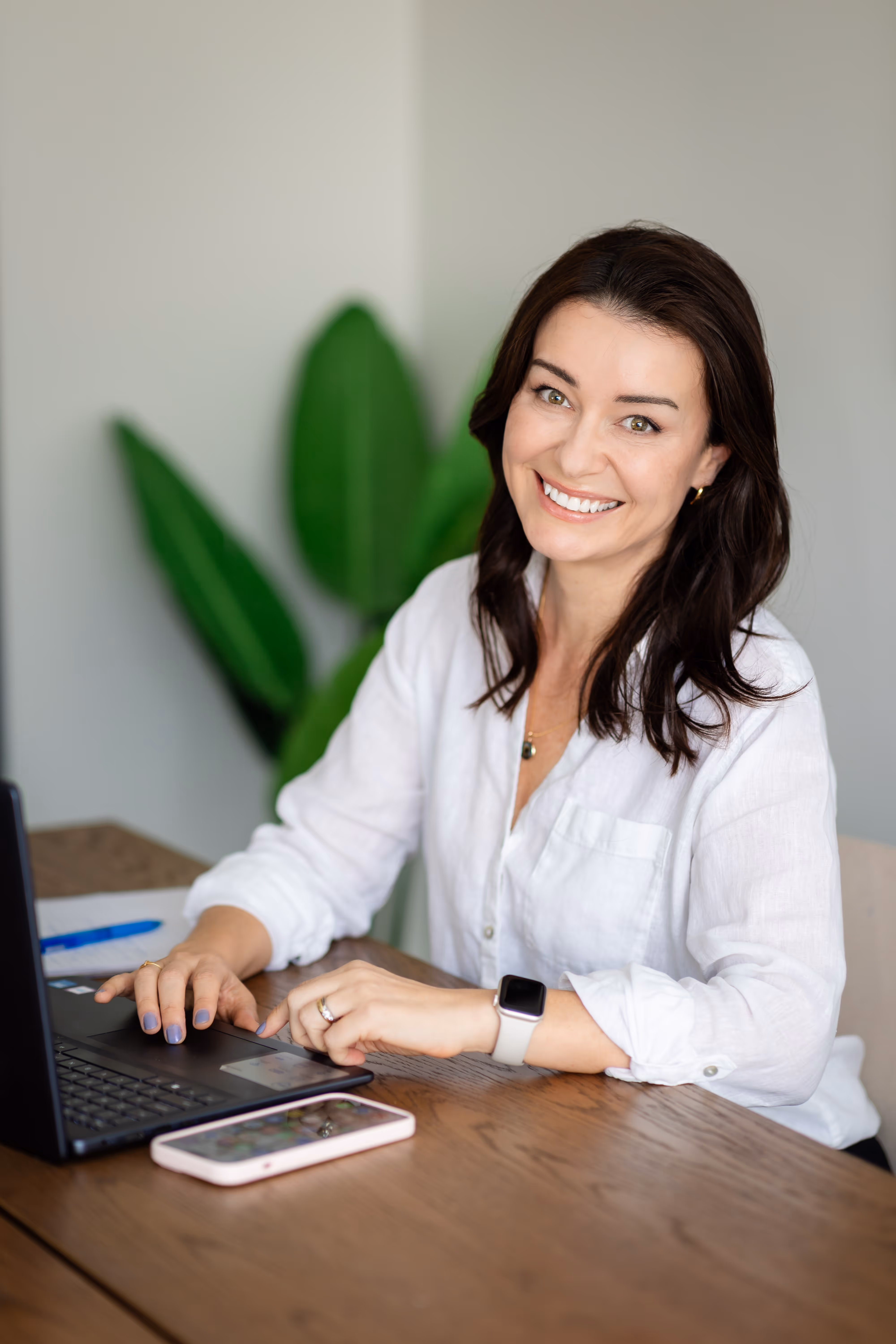 Camila Drehmer, founder of LogicaTalent, smiling while working on her laptop at her desk.