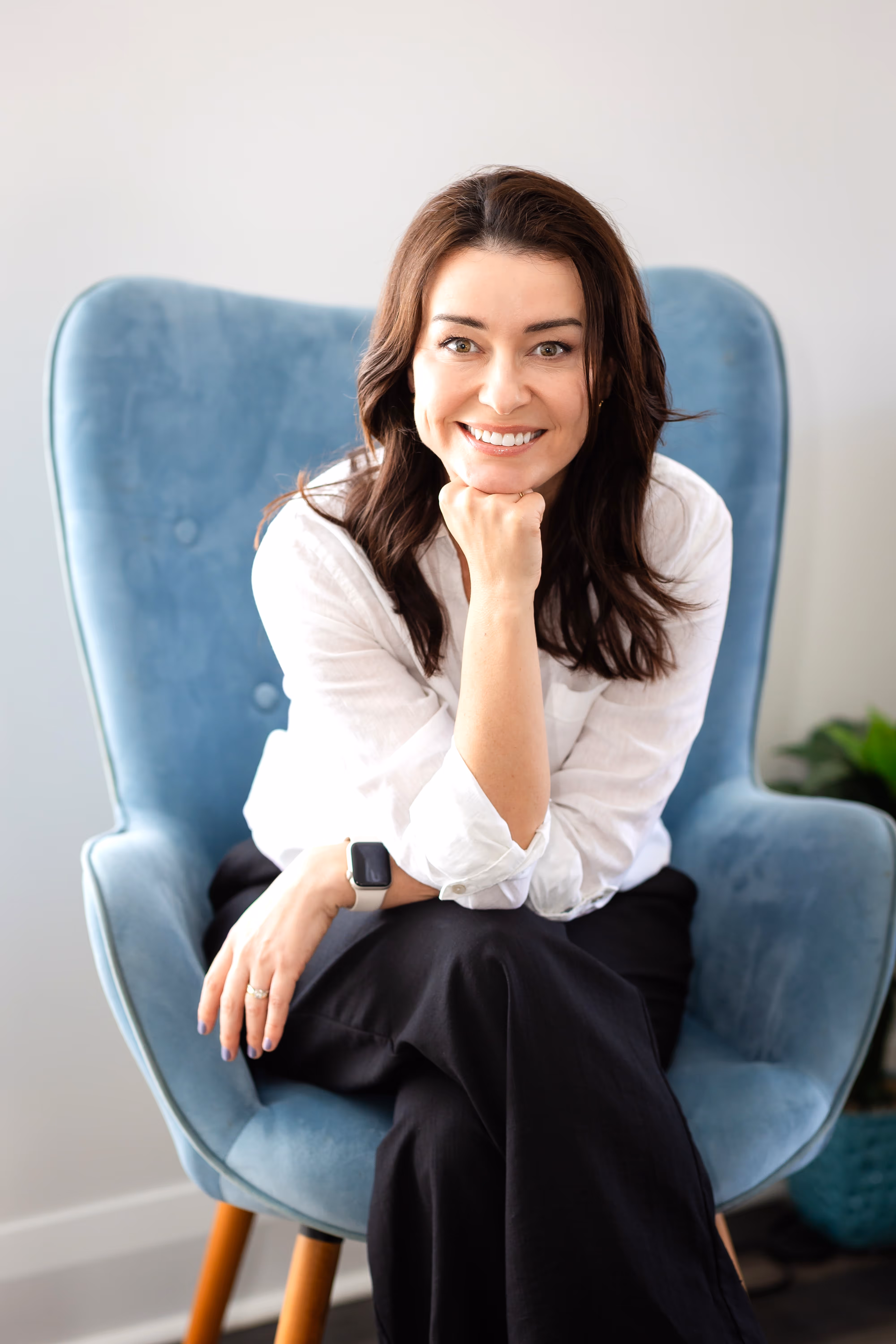 Camila Drehmer, founder of LogicaTalent, sitting on a chair and smiling confidently during a professional portrait session