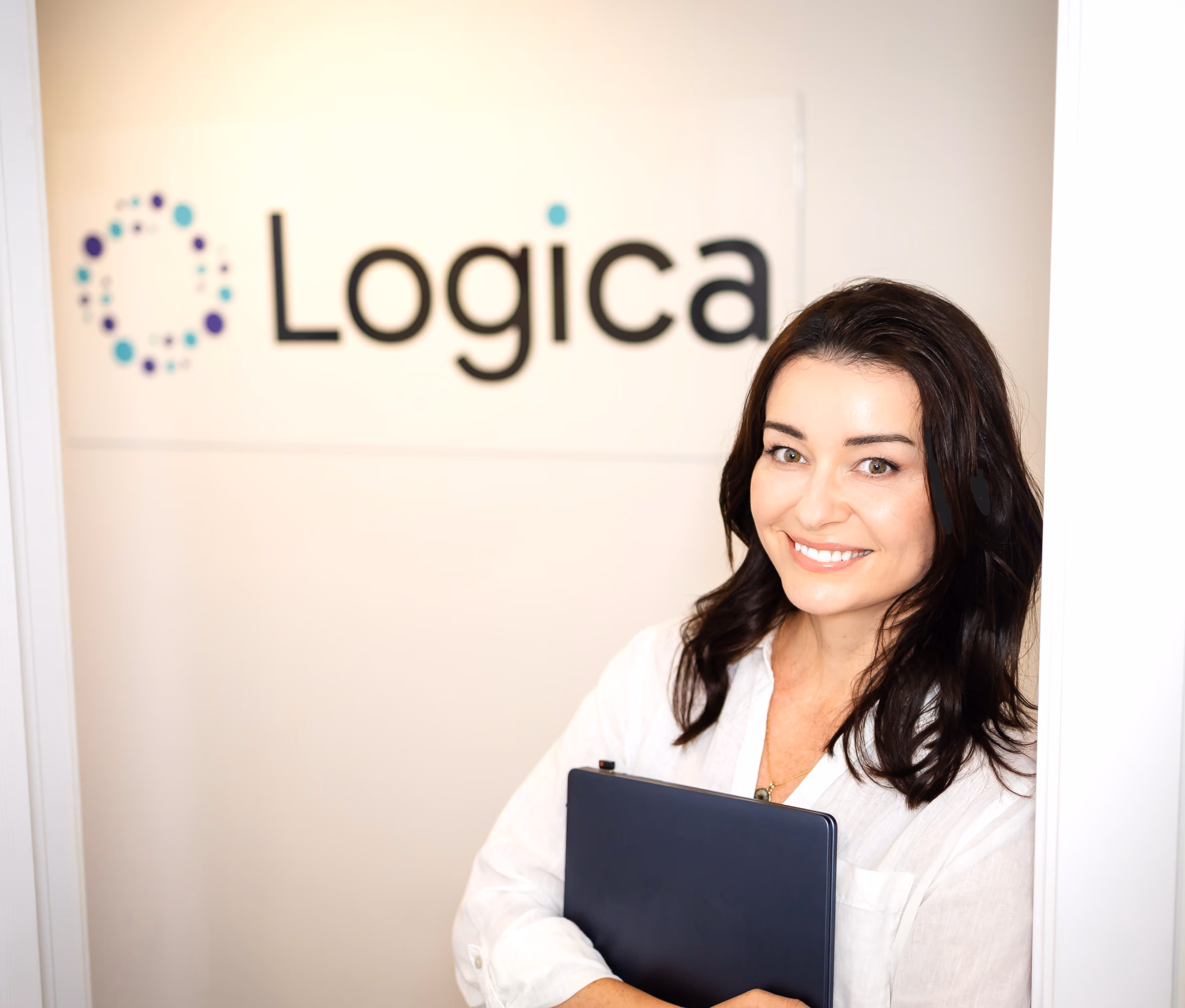 Camila Drehmer, founder of LogicaTalent, smiling and holding a folder in front of the company logo, representing her expertise in career development and Enneagram coaching.