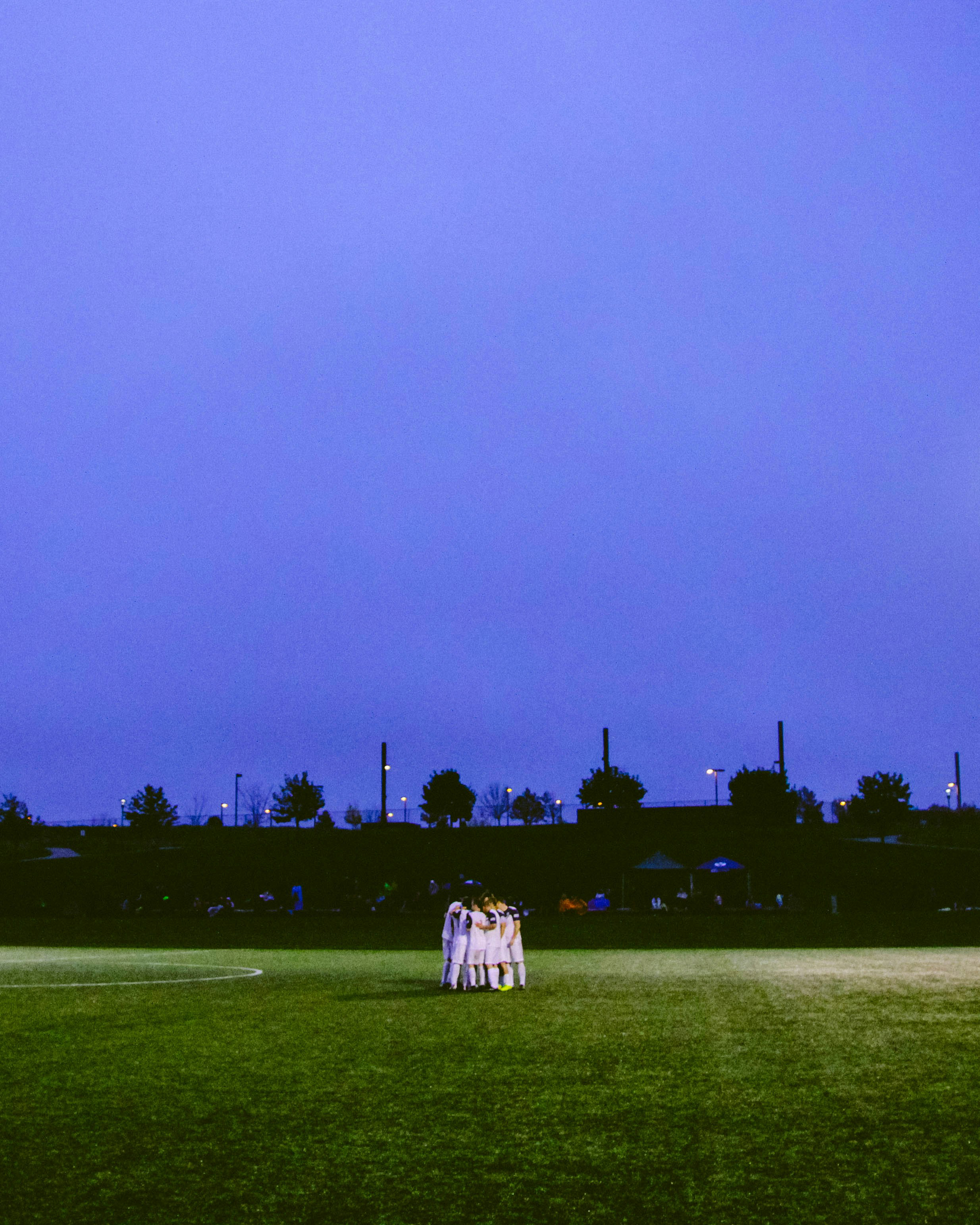 Photo of a football team in a huddle on the pitch.