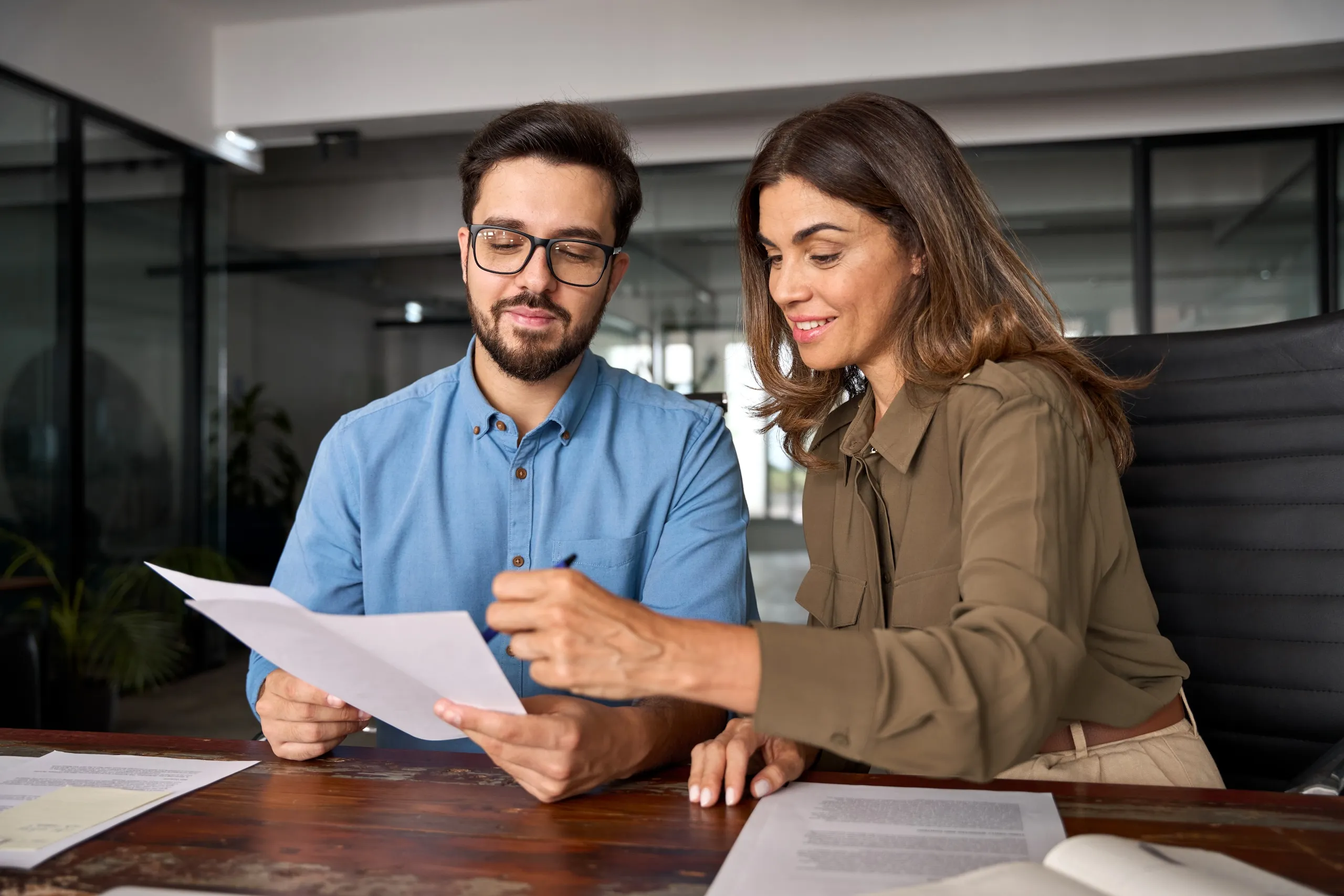A man and woman sitting at a desk looking at papers.