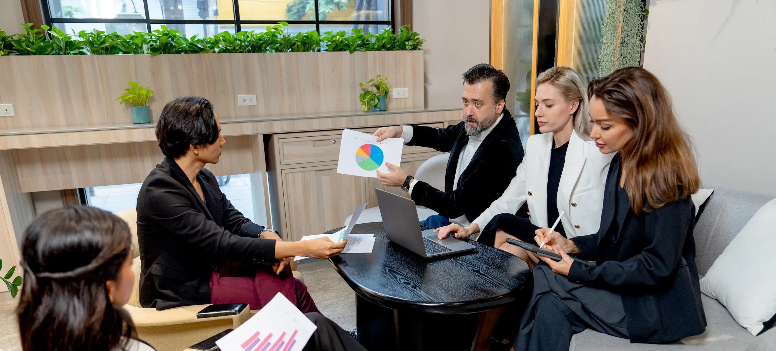 A group of people sitting around a table working on laptops.