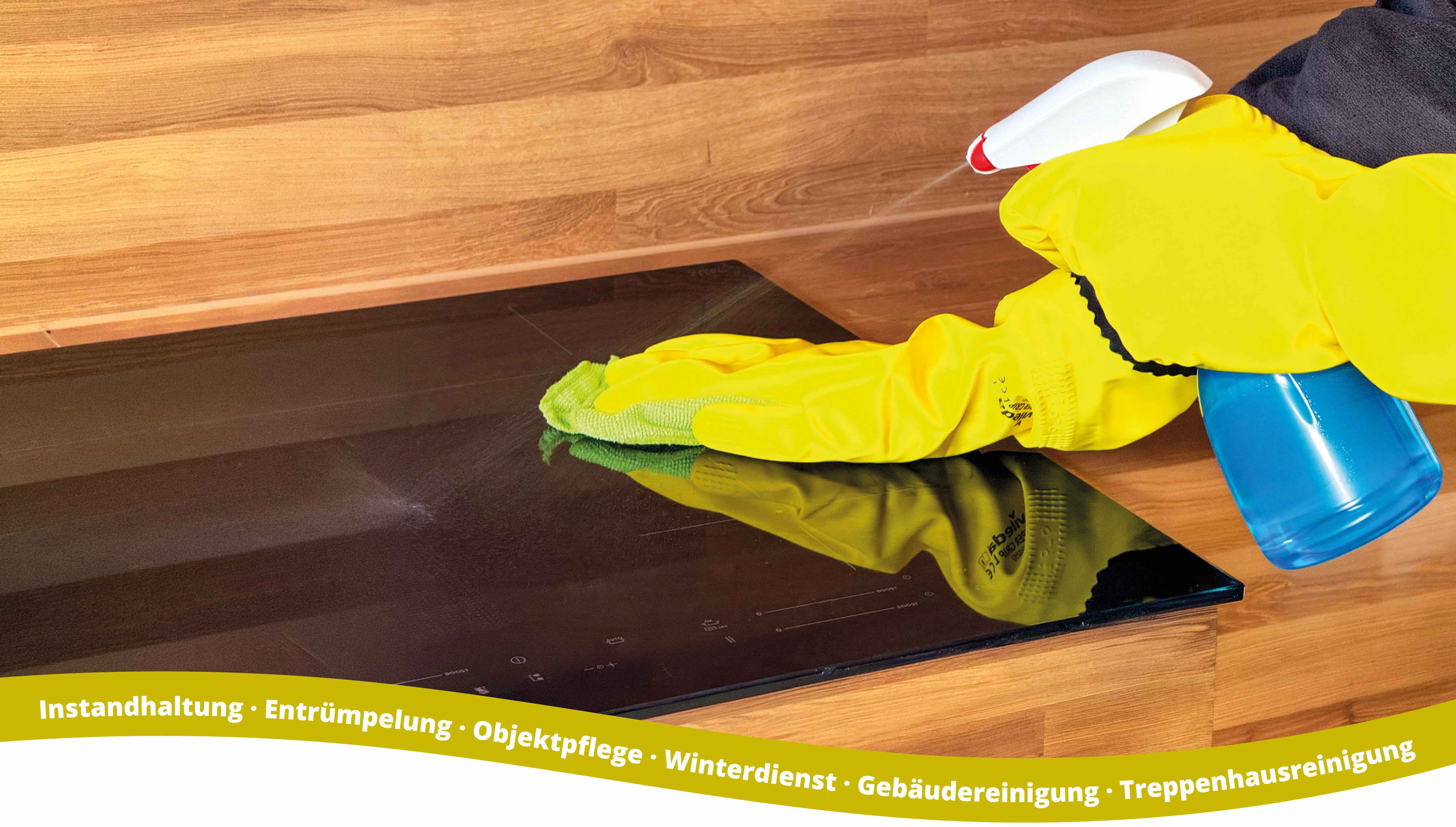 Person wearing bright yellow rubber gloves cleaning a black glass cooktop with a green cloth and spraying cleaner from a white and blue spray bottle, on a wooden countertop background.