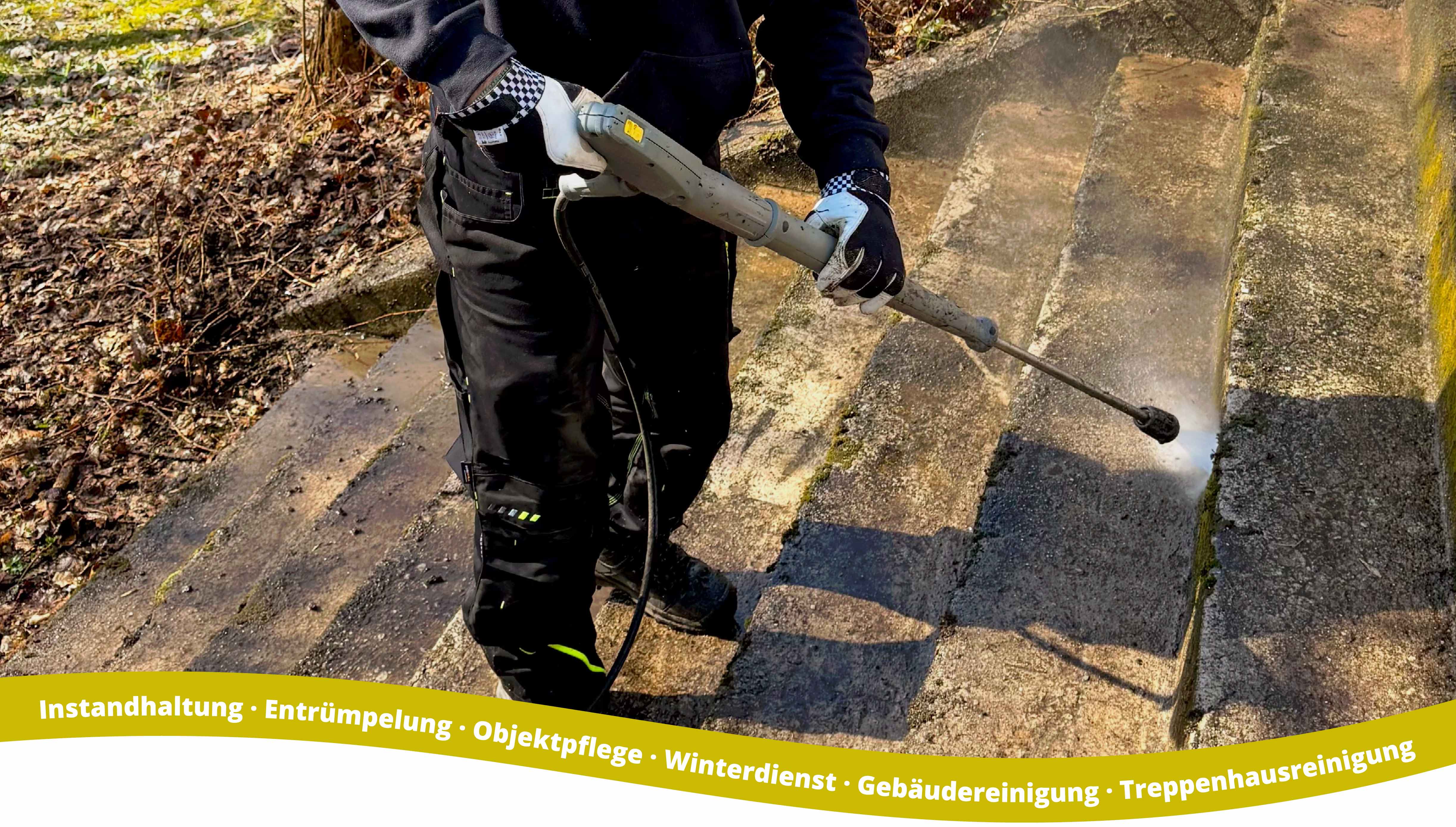 Worker wearing gloves pressure washing a set of concrete outdoor stairs, cleaning dirt and moss from the surface.