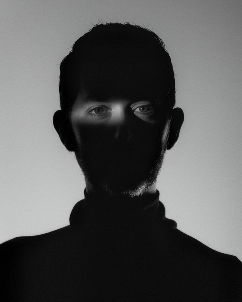 A middle-aged man in dimly lit room and spotlight on eyes