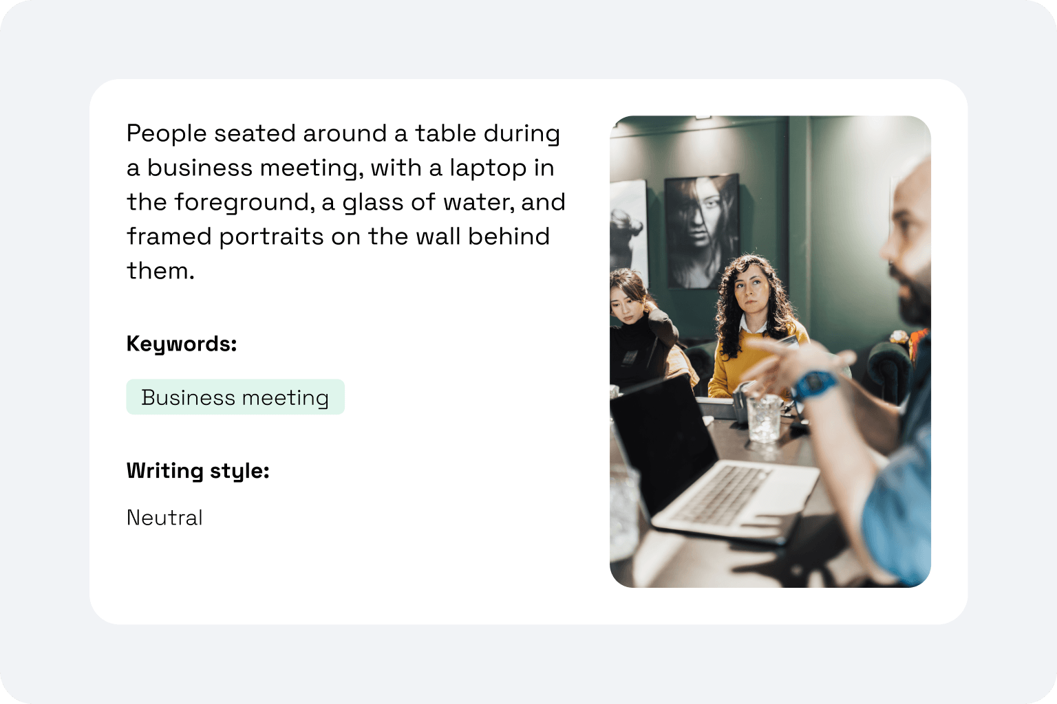 People seated around a table during a business meeting with a laptop and glass of water in the foreground.