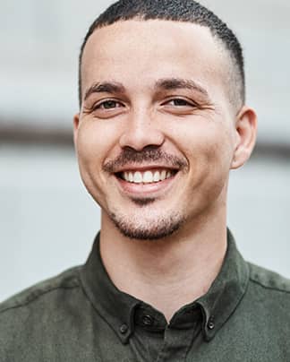 Junger Mann mit natürlichem, selbstbewusstem Lächeln – zufriedener Patient der Q-Zahnärzte Freiburg.