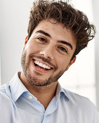 Junger Mann mit strahlendem, weißen Lächeln nach ästhetischer Zahnbehandlung bei den Q-Zahnärzten Freiburg.