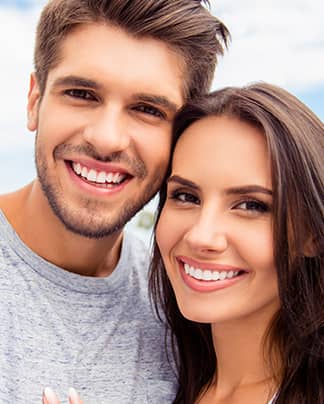 Junges Paar mit strahlendem Lächeln – zufriedene Patienten der Q-Zahnärzte Freiburg.