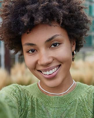 Junge Frau mit strahlendem, natürlichen Lächeln – zufriedene Patientin der Q-Zahnärzte Freiburg.