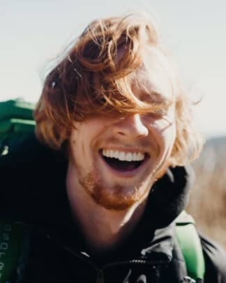 Junger Mann mit freiem, strahlendem Lächeln und gesunden Zähnen zeigt die Wirkung moderner ästhetischer Zahnbehandlungen bei den Q-Zahnärzten Freiburg.