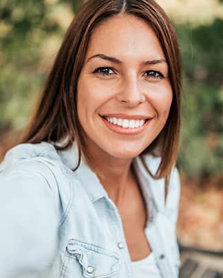 Lachende Frau mit natürlichen, weißen Zähnen nach professioneller Zahnbehandlung bei den Q-Zahnärzten Freiburg.