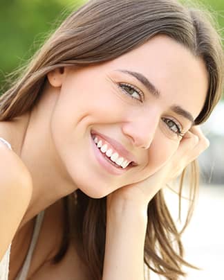 Junge Frau mit strahlend weißen Zähnen lächelt entspannt nach professioneller Zahnbehandlung bei den Q-Zahnärzten Freiburg.