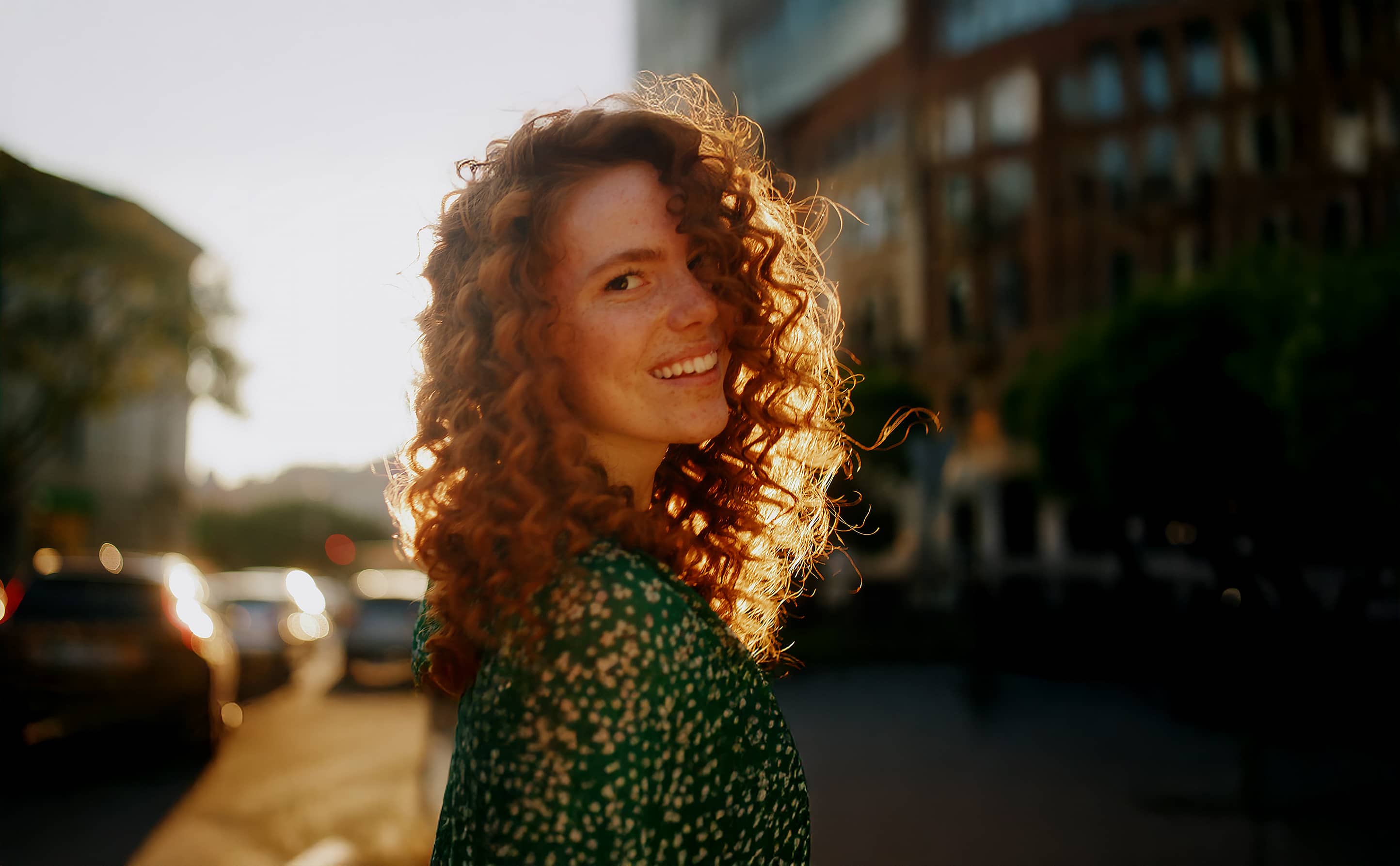 Frau mit strahlendem Lächeln in der Abendsonne – natürlich schöne Zähne durch hochwertige Veneers bei den Q-Zahnärzten Freiburg.