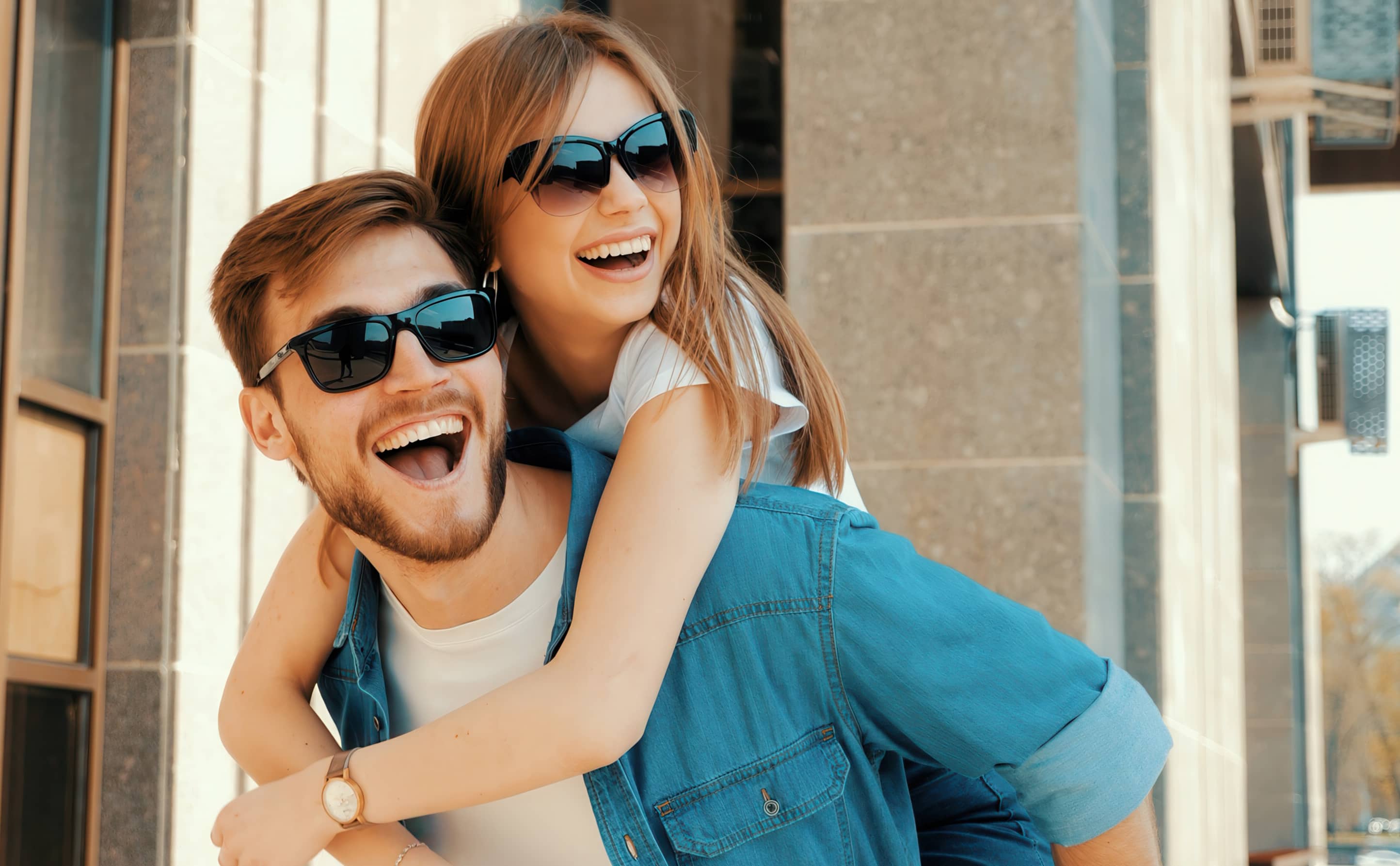 Bleaching Freiburg – strahlend weißes Lächeln: Glückliches Paar lacht gemeinsam in der Sonne nach erfolgreicher Zahnaufhellung.