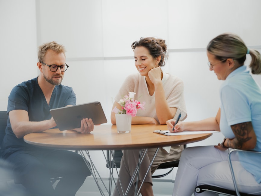 Beratung zur unsichtbaren Zahnspange in Freiburg – Patientin bespricht mit dem Zahnarzt die digitale Aligner-Planung, während eine Mitarbeiterin alle Details dokumentiert.