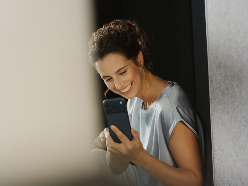 Bleaching Q-Zahnärzte Freiburg – Patientin zeigt im Video-Call stolz ihr aufgehelltes Lächeln.