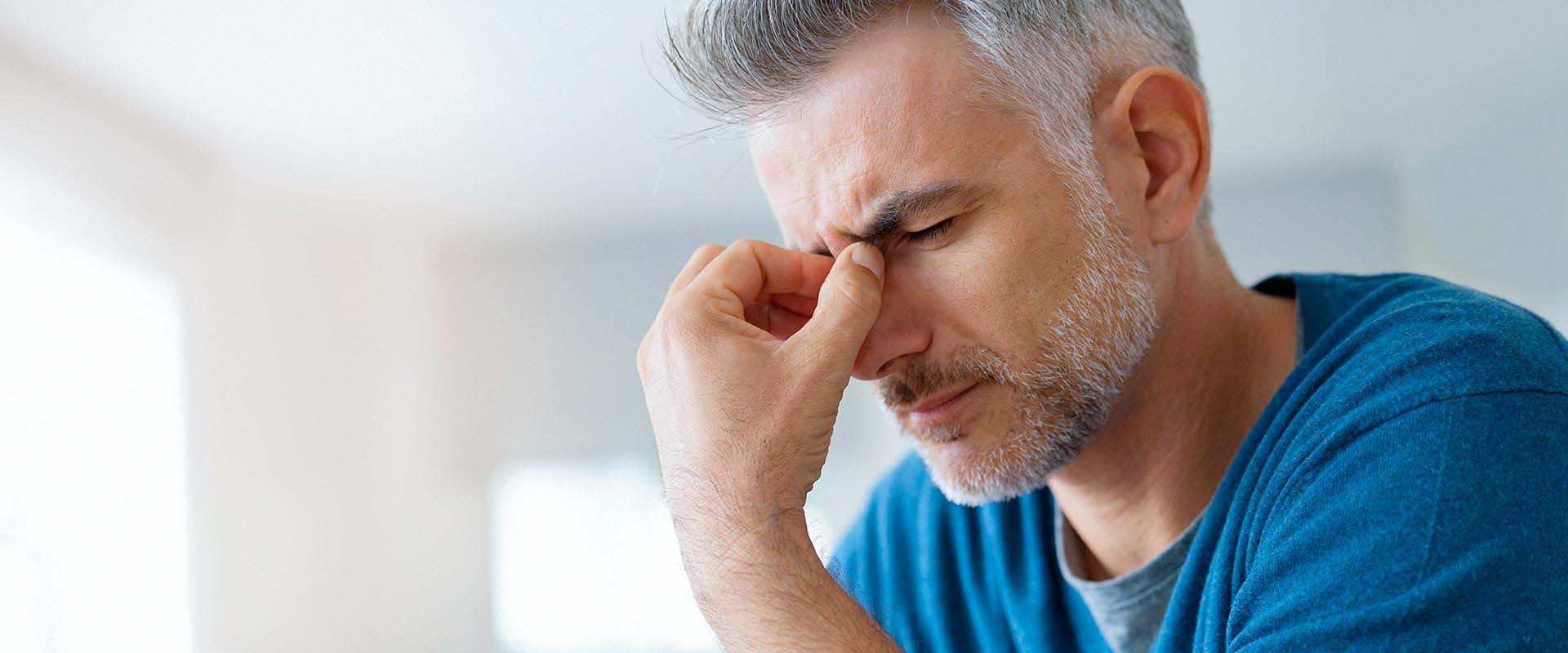 Mann mit starken Kopf- und Gesichtsschmerzen – typisches Symptom einer CMD, die bei Q-Zahnärzte Freiburg diagnostiziert und behandelt wird.