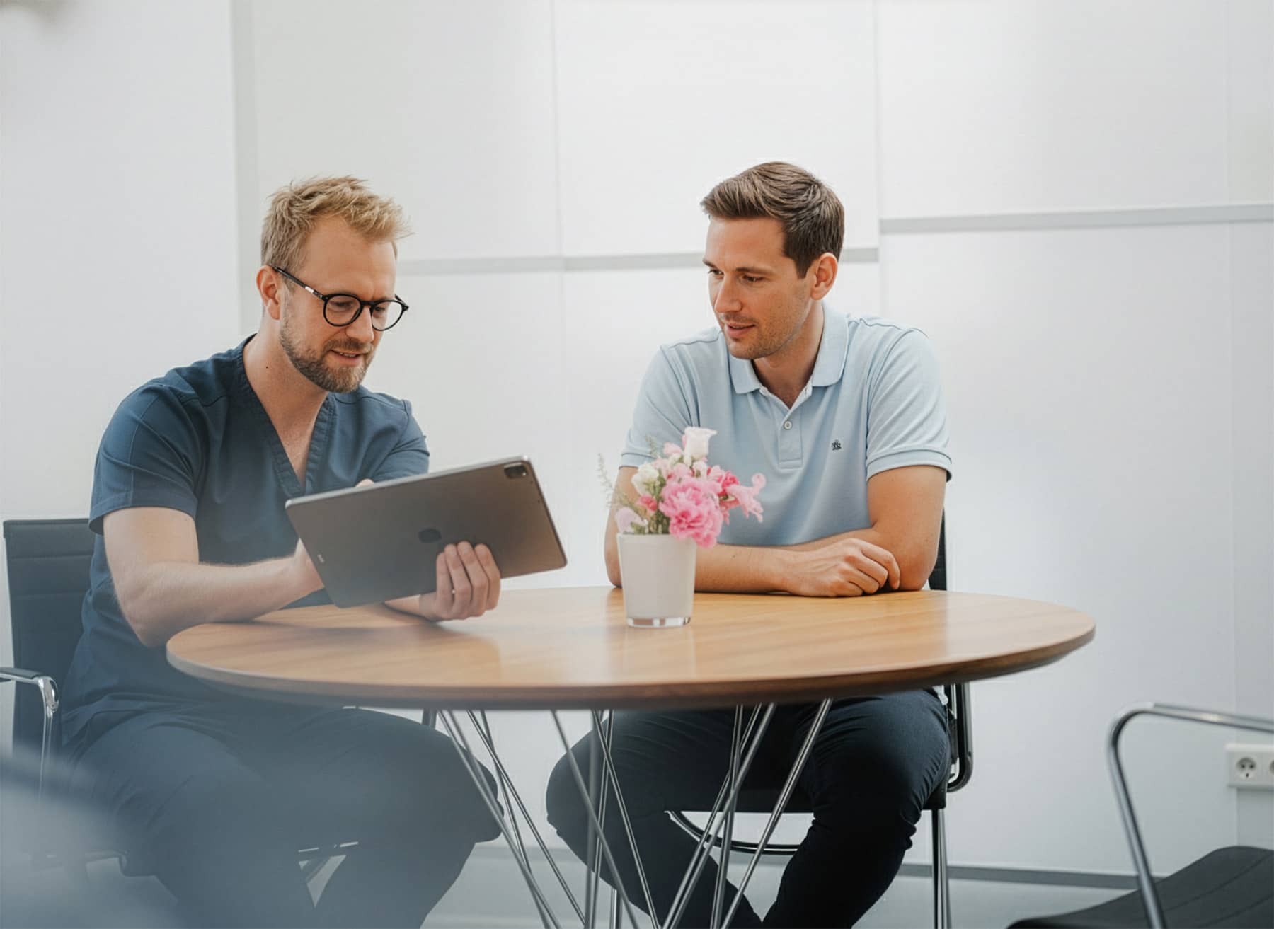 Zahnarzt der Q-Zahnärzte Freiburg erklärt einem Patienten die digitale CMD-Diagnostik und Therapieoptionen am Tablet.