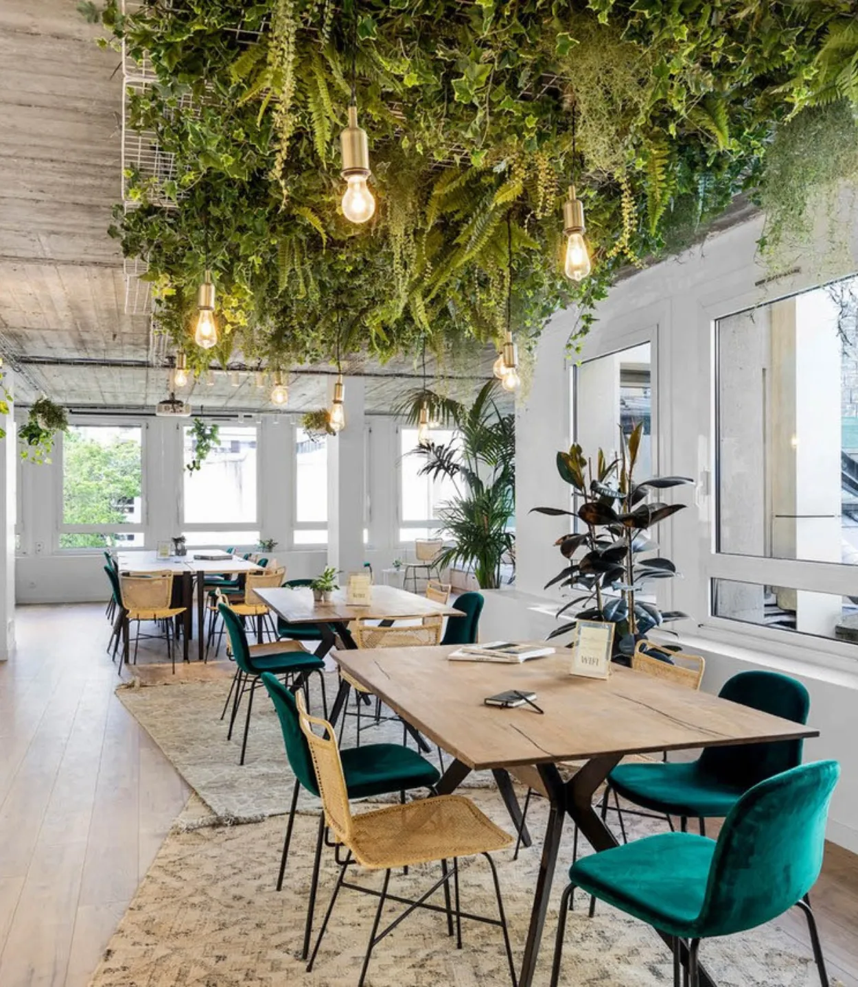 Open space avec tables variées et fausse verdure chez Keeze La Galerie Champs-Élysées, parfait pour une salle de réunion ou un espace de coworking à Paris 8e.
