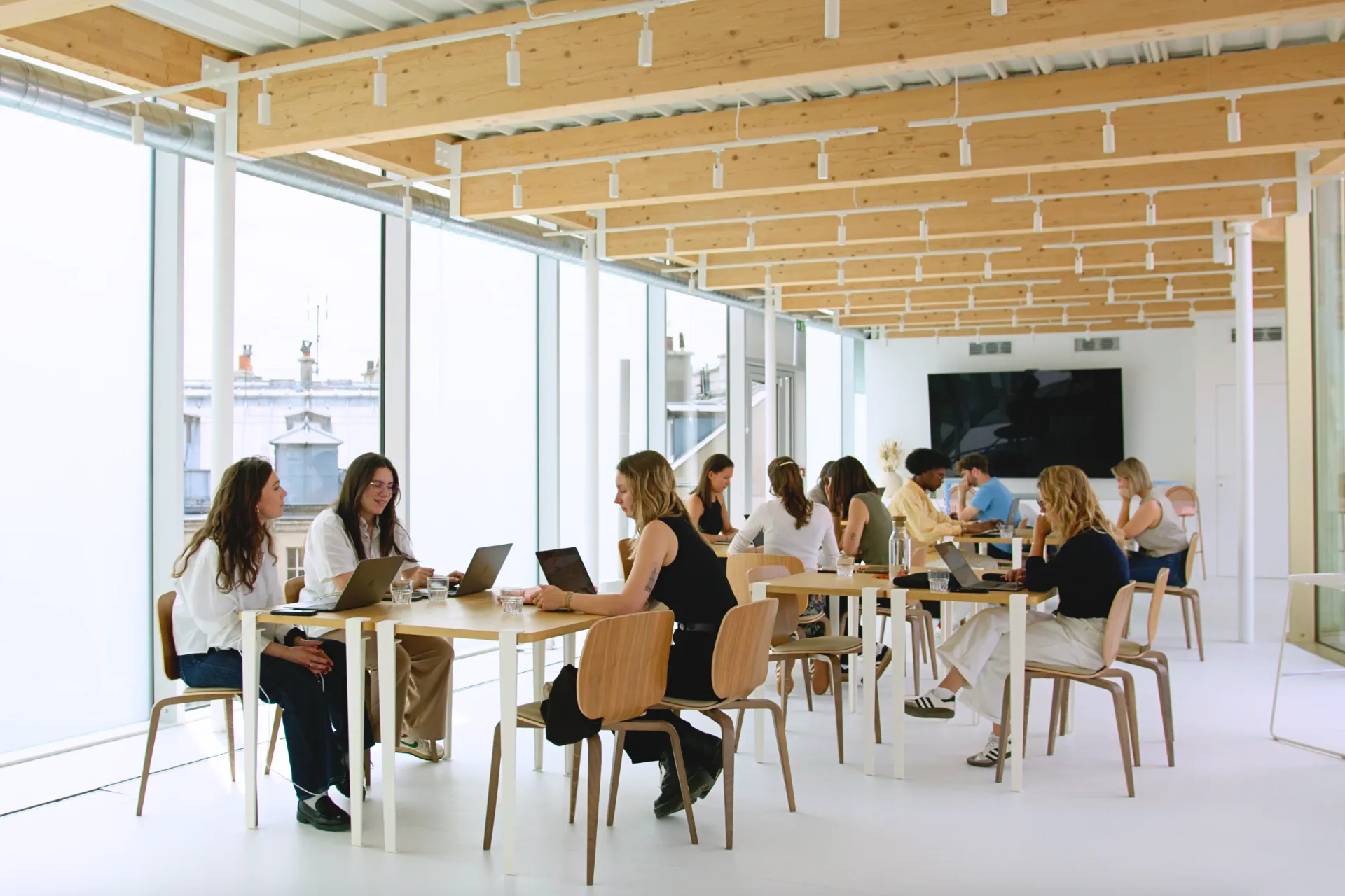 Collaboration entre collègues dans un open space à Paris, espace de coworking adapté aux équipes, réunions informelles et projets partagés.