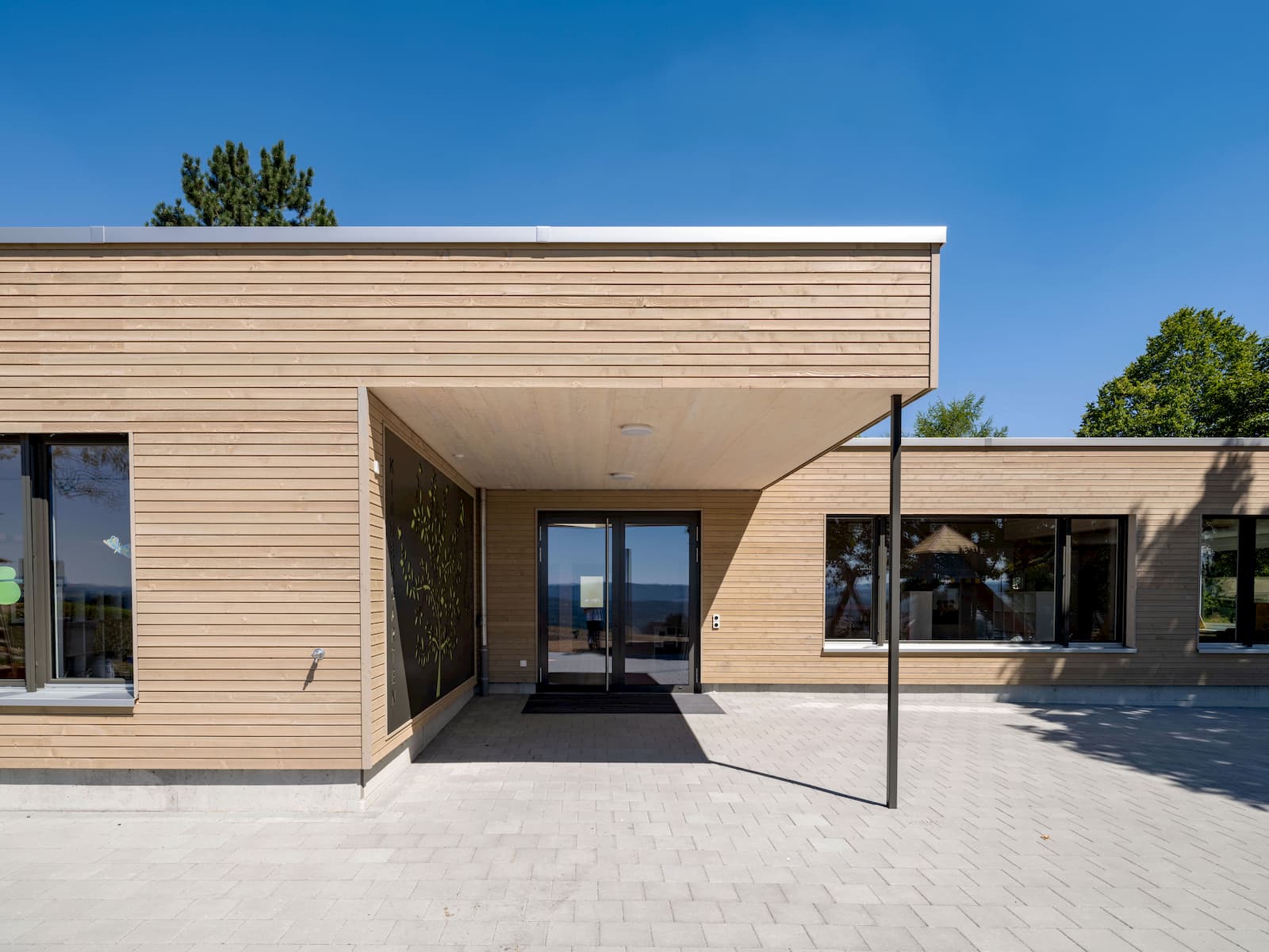 Einstöckiger Kindergarten mit Holzfassade und grossen Fenstern