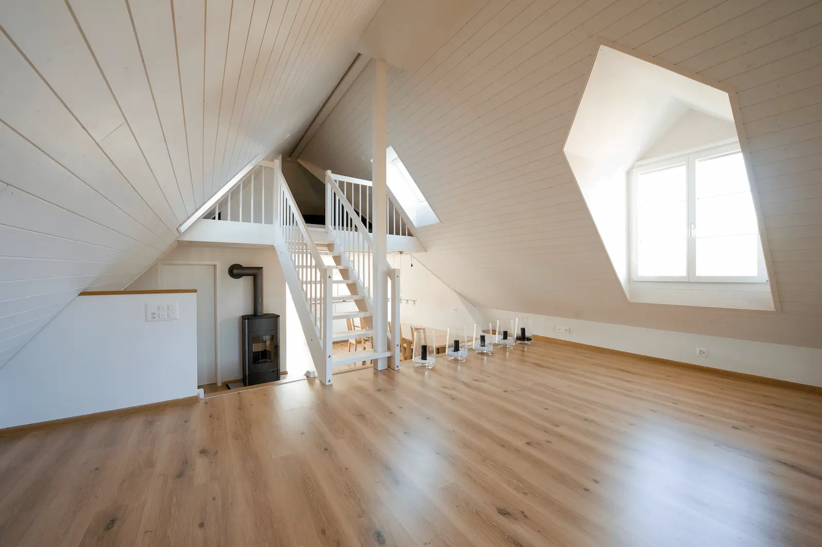 Ausgebautes Dachgeschoss mit Holzofen, Dachschrägen und Fenster in saniertem Gebäude in Würenlos