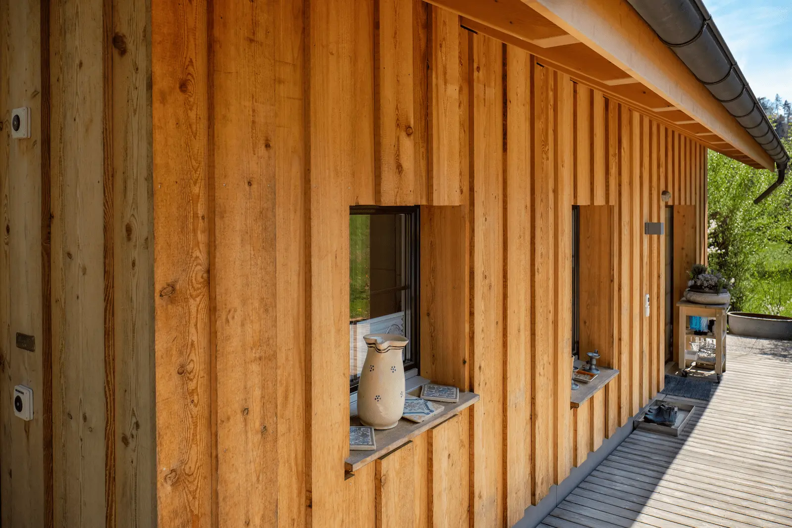 Fassadenansicht eines Anbaus mit vertikaler Naturschalung, hinterlüfteter Holzfassade und eingelassenen Fensteröffnungen mit Fensterbank, Hettenschwil