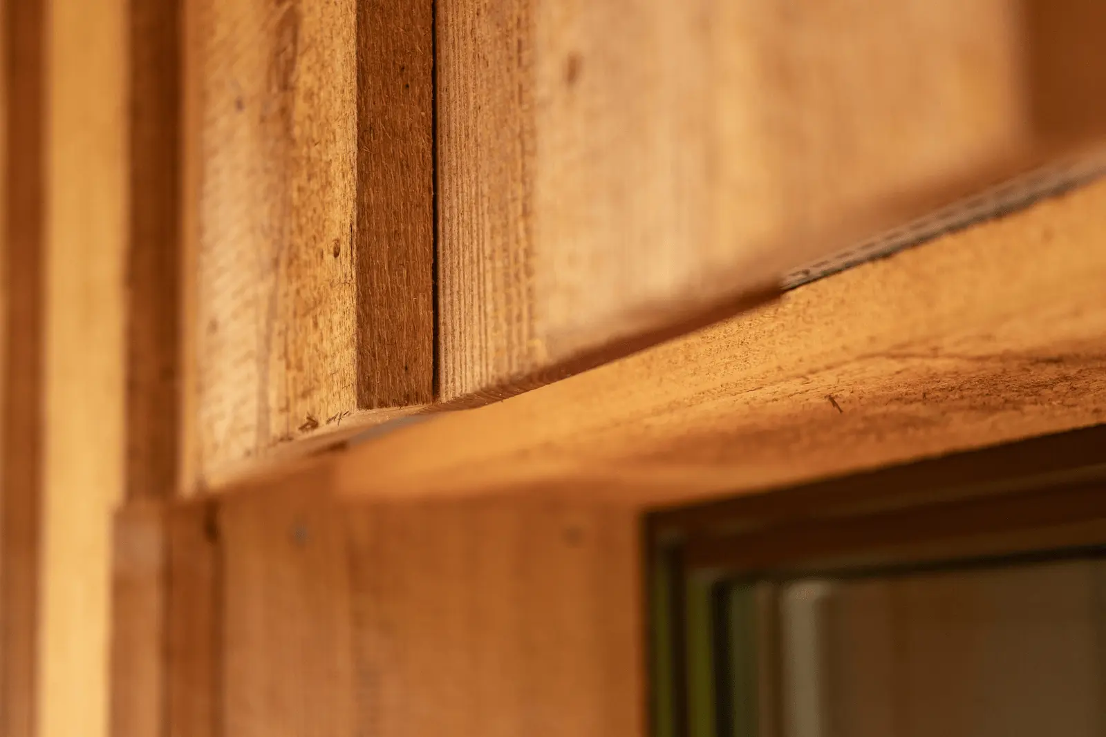 Nahaufnahme einer hinterlüfteten Holzfassade mit vertikaler Naturschalung, sichtbare Fugenhinterlüftung oberhalb eines Fensters, Anbau in Hettenschwi