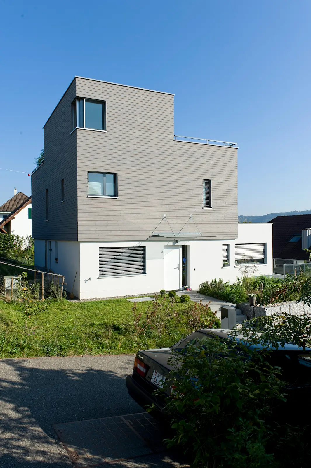 Vorderansicht Neubau Einfamilienhaus in Untersiggenthal mit Holzelementbau, horizontaler Holzfassade und weissem Sockelgeschoss